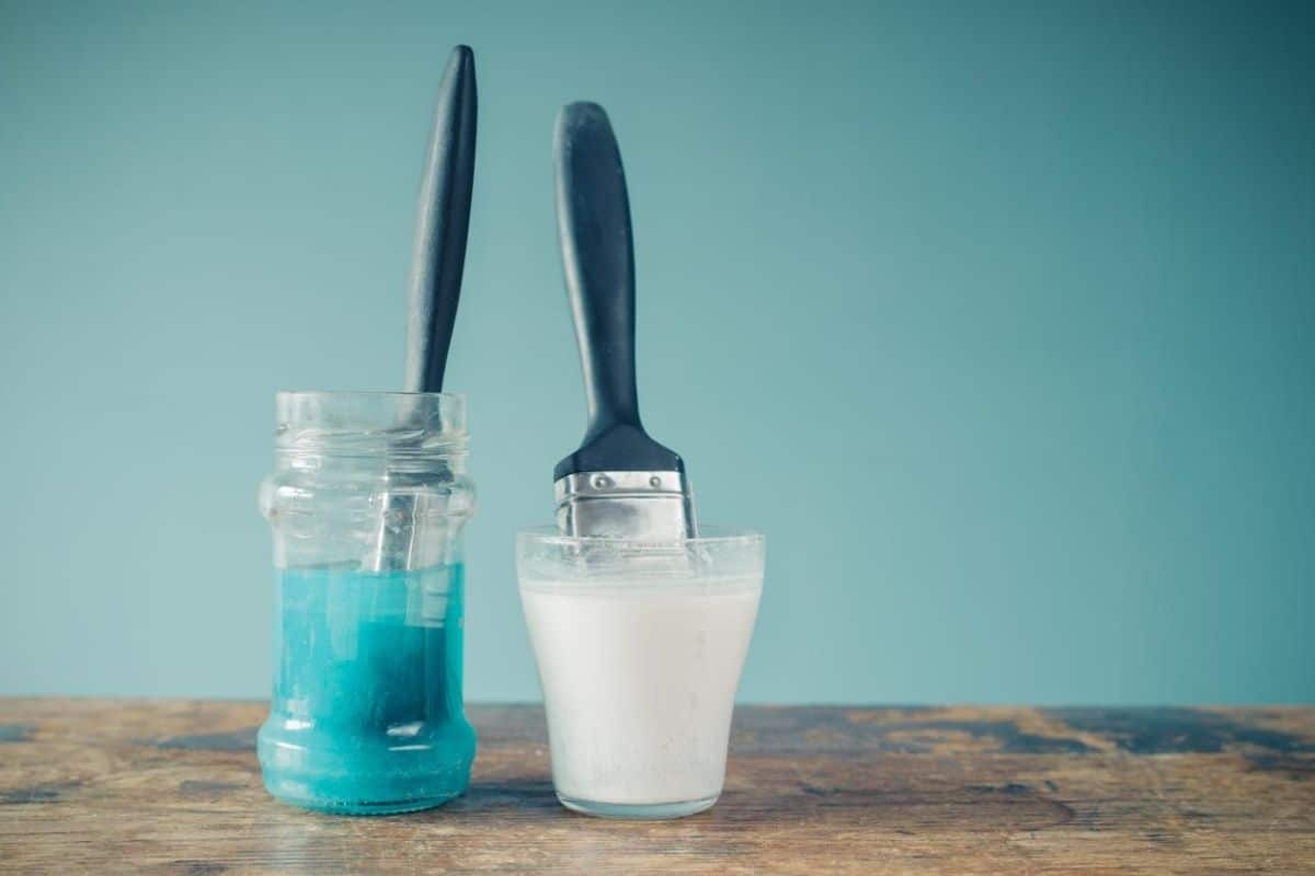 two paint brushes soak in jars
