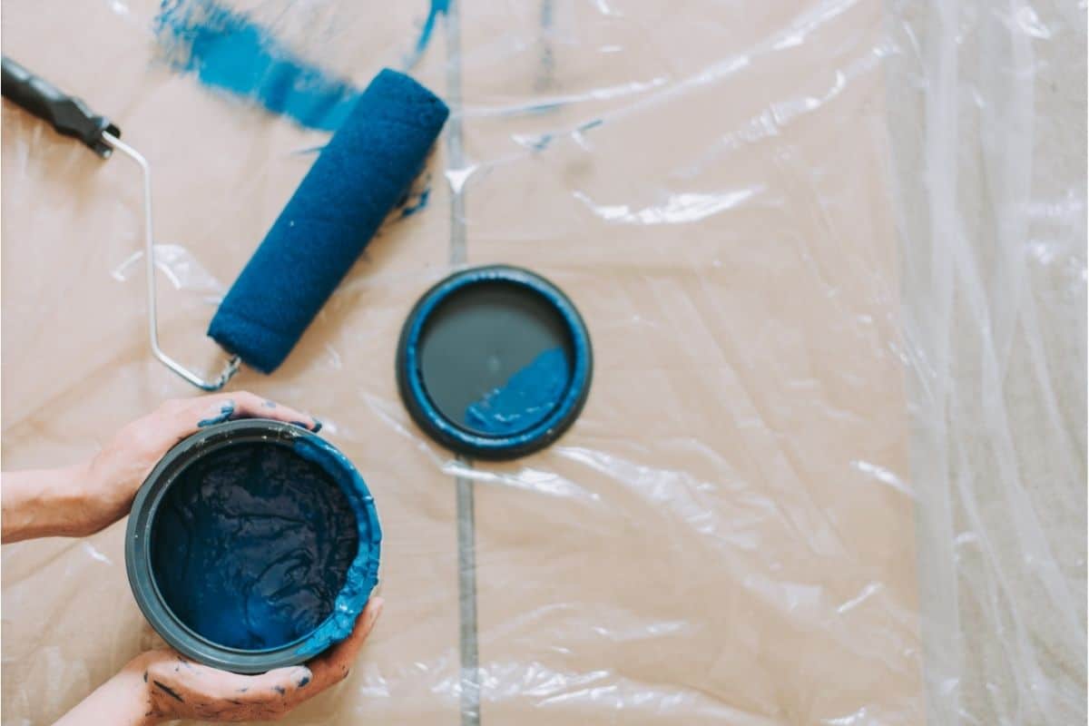 hands holding blue paint can