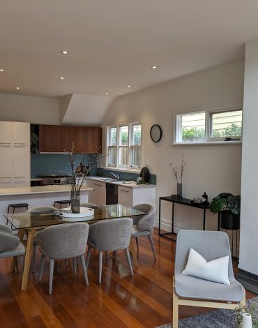 Modern kitchen and dining room with sleek design, wooden flooring, and contemporary furniture.