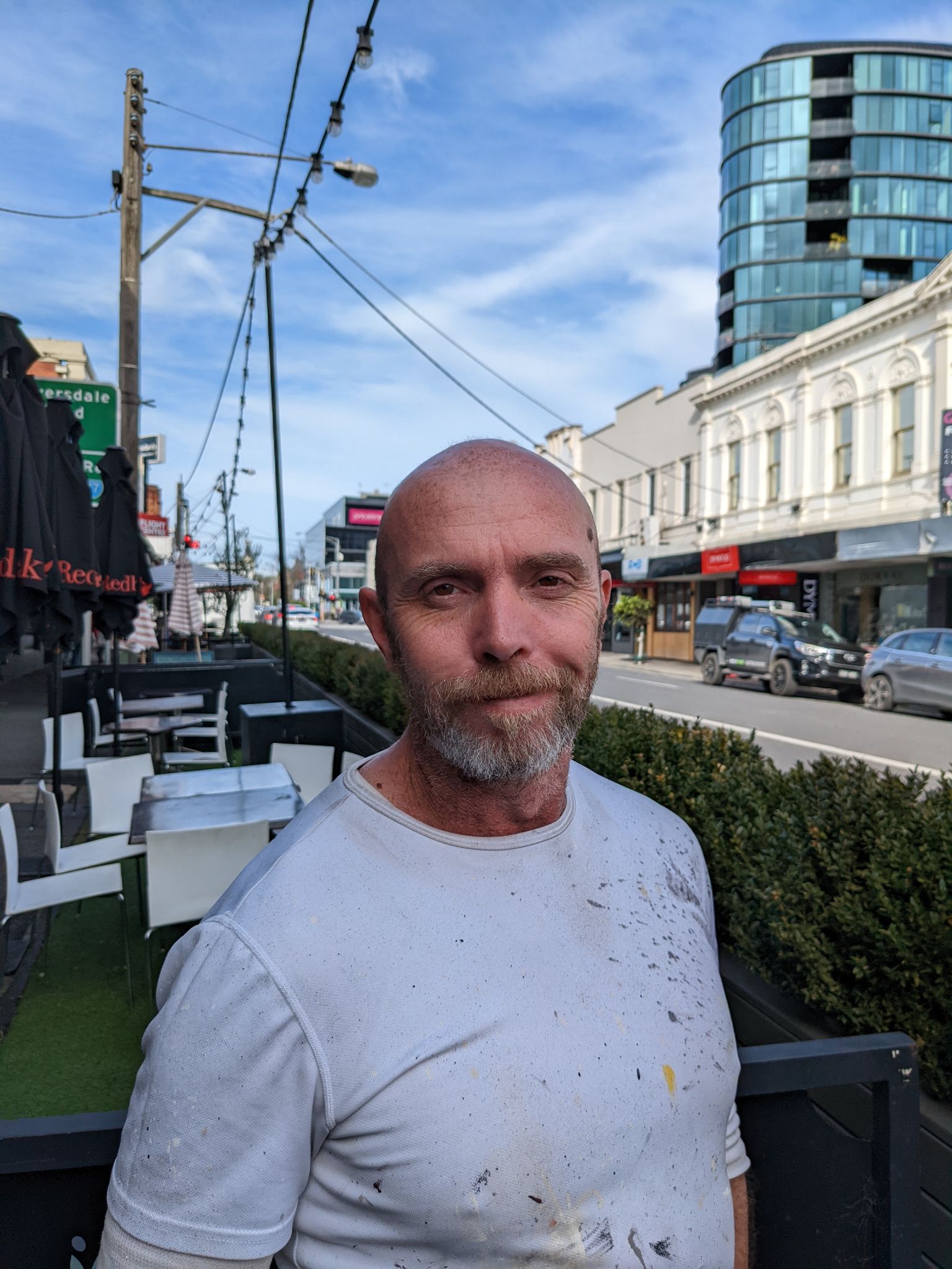 Painter in a White Shirt With Paint Stains Standing on a Busy Street