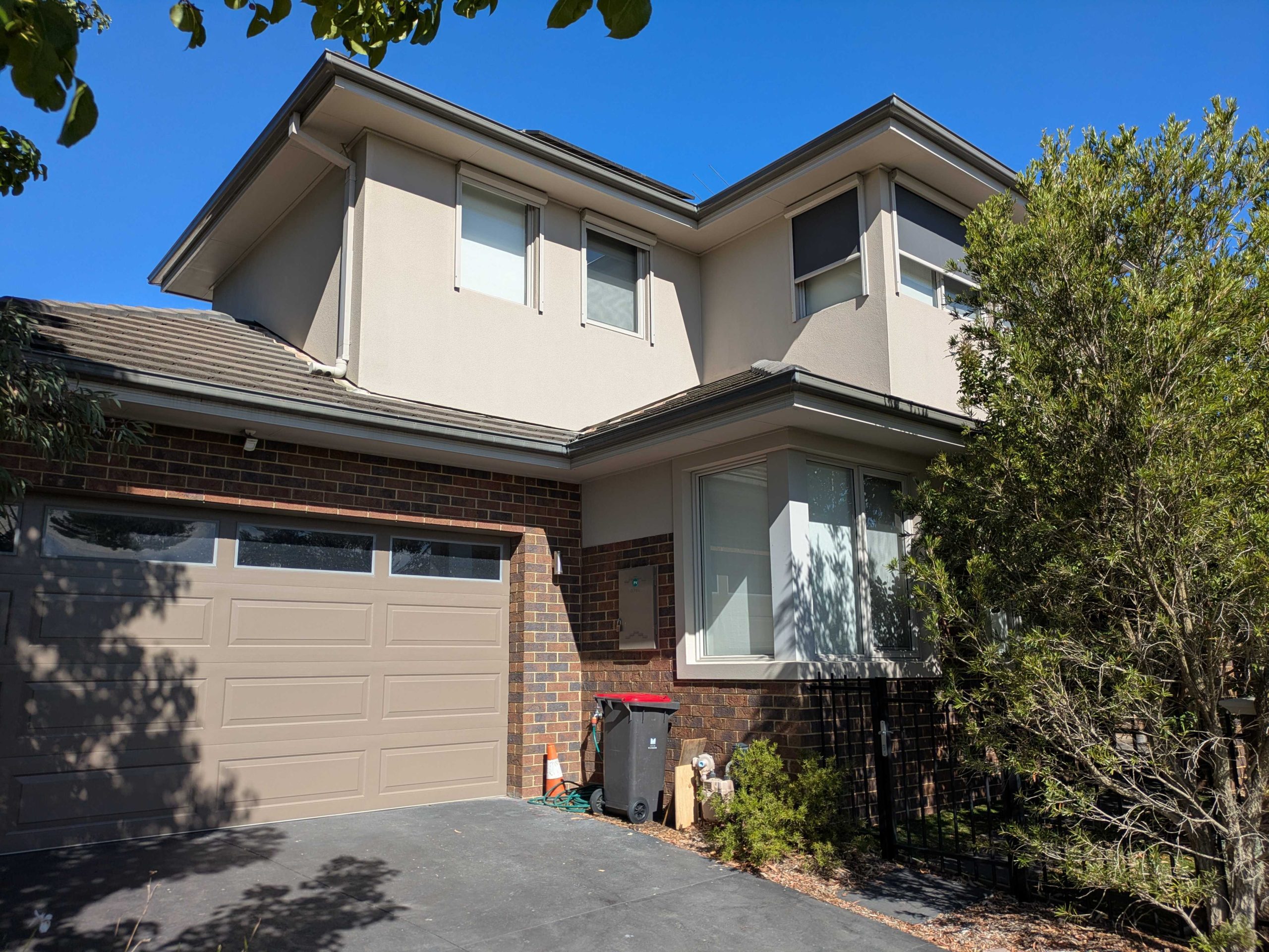 Freshly painted modern two-story home with a combination of brick and neutral-colored exterior walls.
