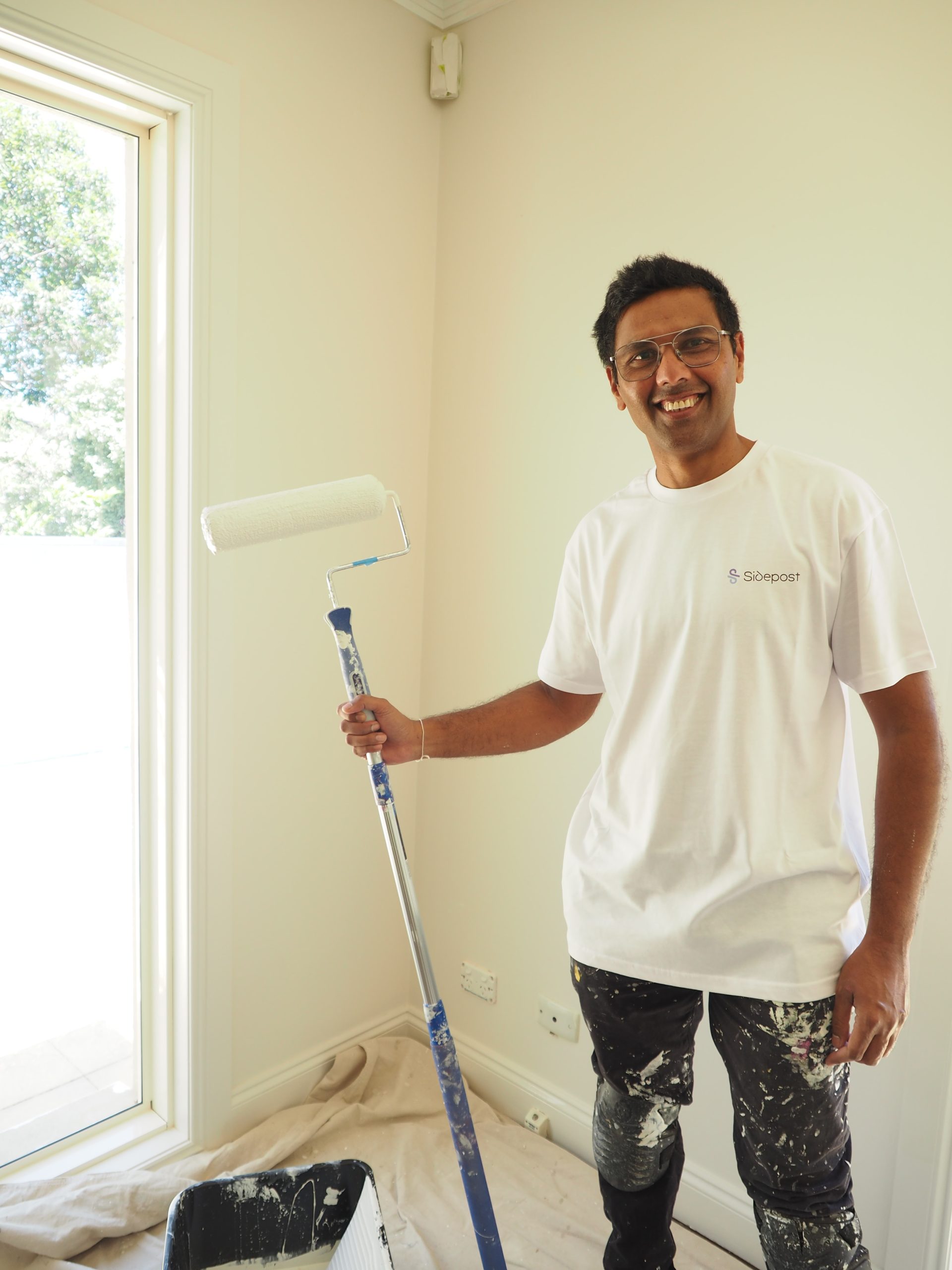Painter Holding a Roller Brush, Smiling in a Brightly Lit Room