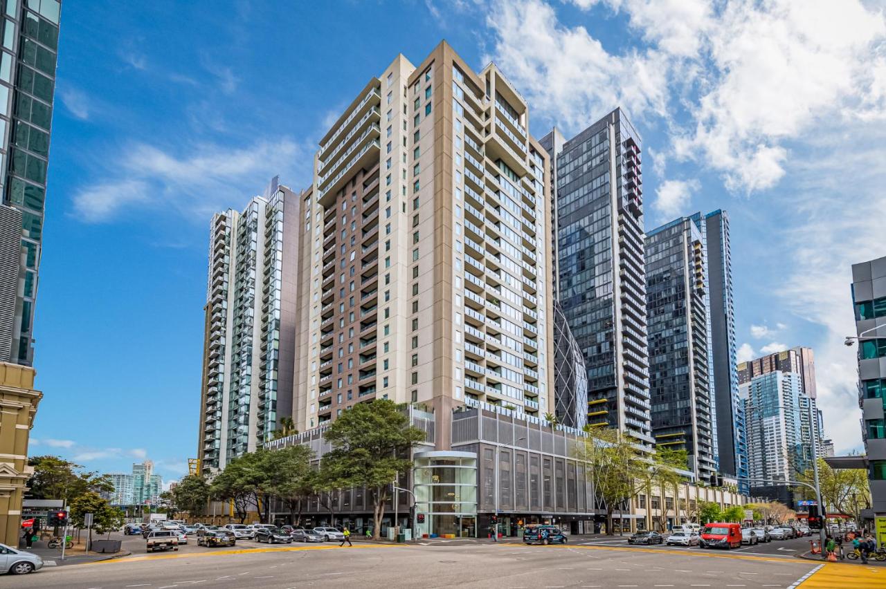 High-rise apartment buildings in a bustling urban setting under a bright blue sky.