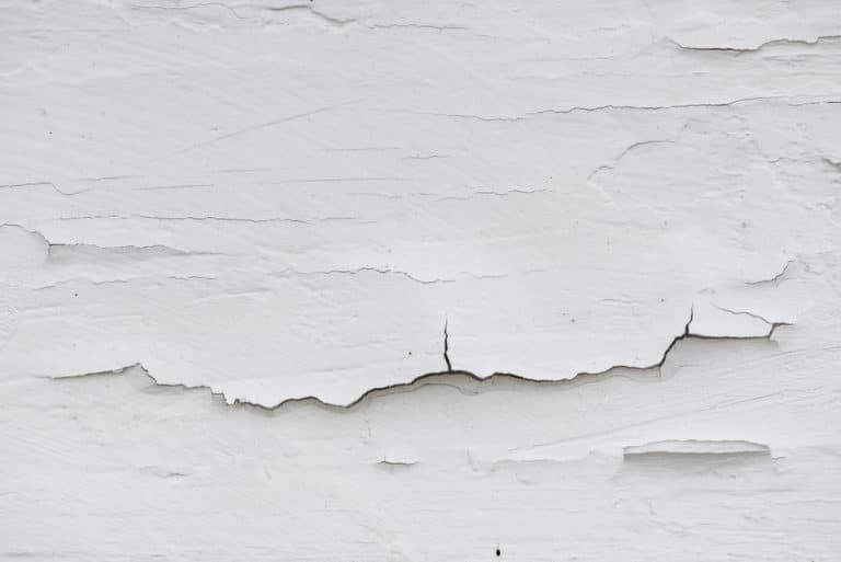 A close-up of peeling white paint on a wall.