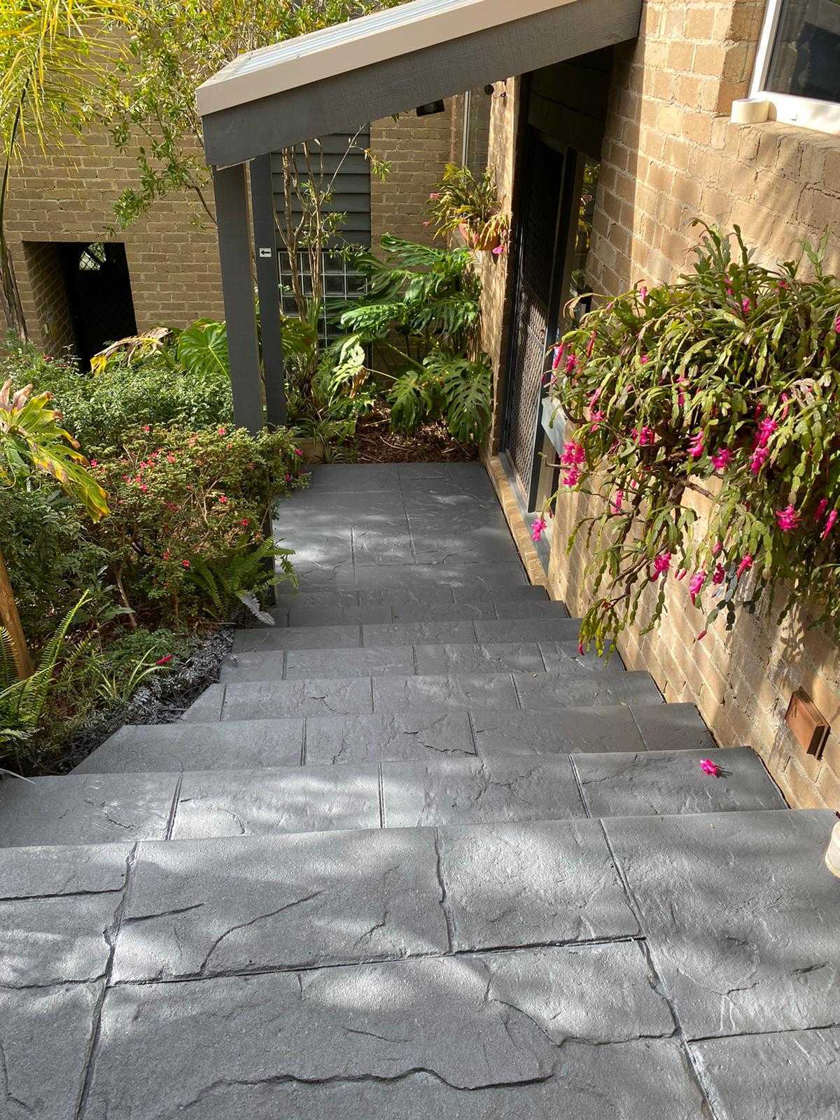Decorative concrete steps leading to a home entrance with surrounding lush greenery
