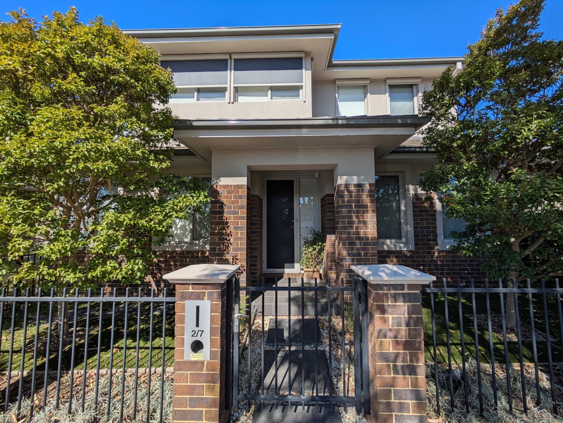 Modern two-story home with a fresh exterior paint finish, featuring a blend of neutral tones and brick accents.
