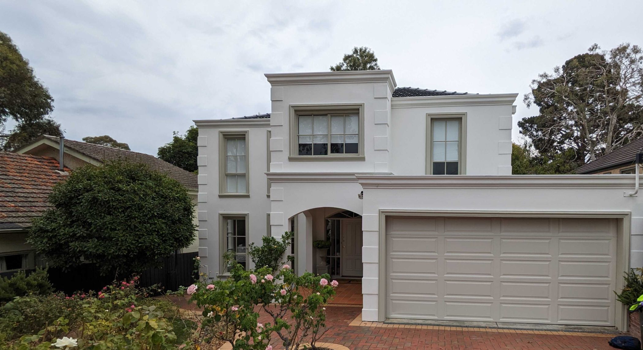 Exterior view of a modern white house with a garage and garden.