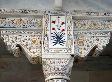 Intricate marble column with floral inlay designs in traditional architectural style.
