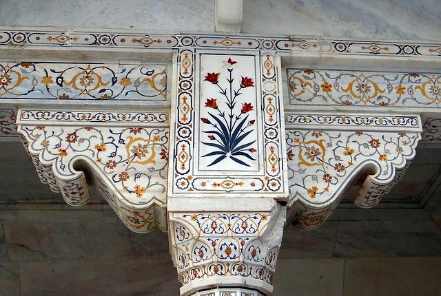 Intricate marble column with floral inlay designs in traditional architectural style.