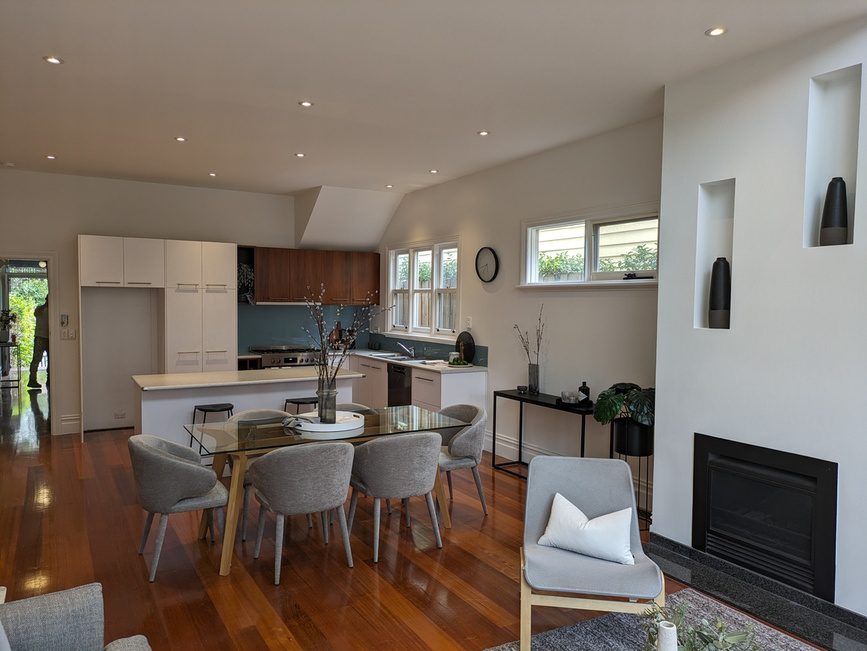 Modern open-plan kitchen and living area with sleek design, wooden flooring, and neutral-toned furniture.