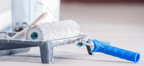 Paint Roller Resting in a Tray with Blue Handle
