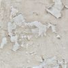 Peeling paint on a damaged wall showing cracks and flaking layers.