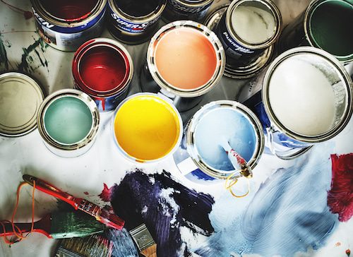 Open Paint Cans With Various Colors and Brushes on a Messy Surface