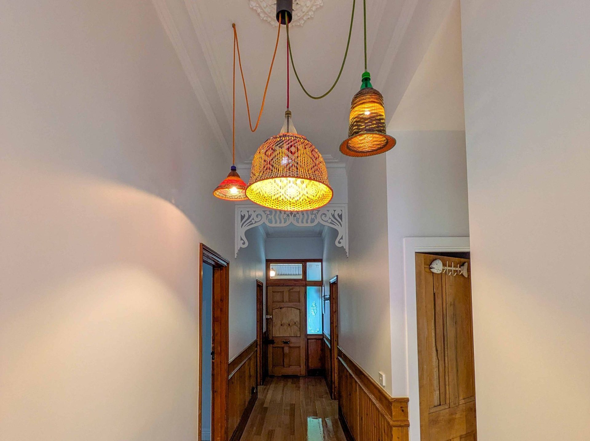 Brightly Lit Hallway with Wooden Accents and Unique Hanging Pendant Lights