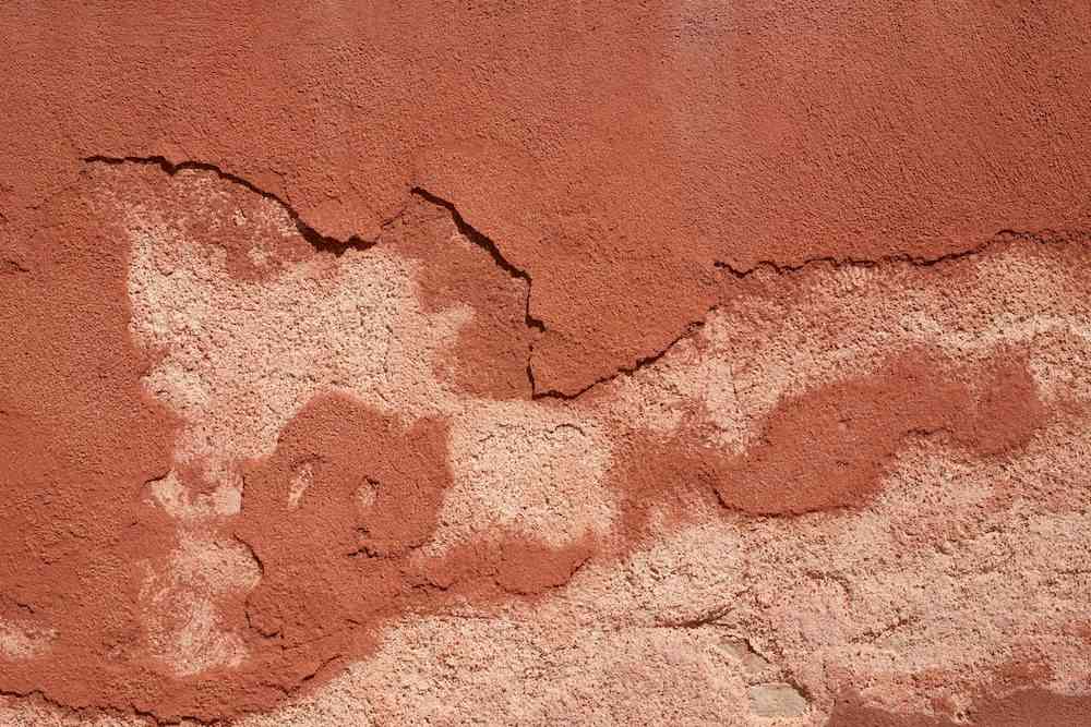 Close-up of cracked and peeling red wall texture.