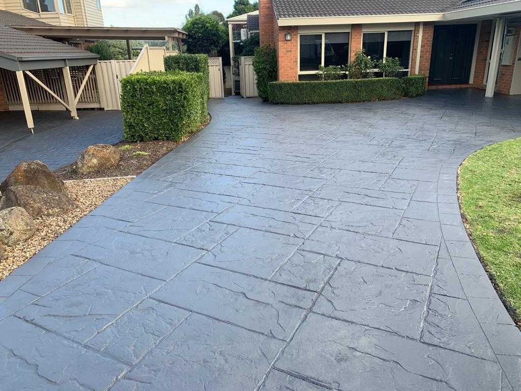 Professional concrete driveway painting with decorative slate pattern finish in residential setting